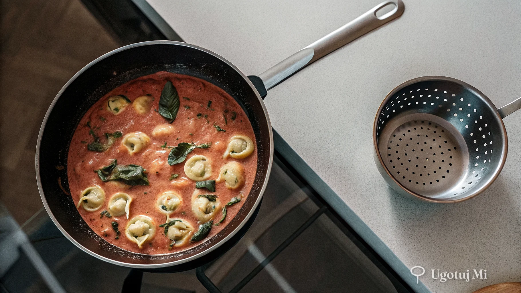Sos pomidorowo-śmietankowy ze szpinakiem na patelni obok odcedzonych tortellini | ugotujmi.pl